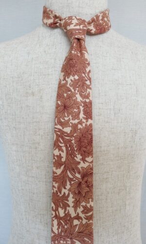 Get ready to add a touch of British charm and naturalistic flair to your outfit with our Chrysanthemum William Morris Tie. This design is all about embracing the quiet rebellion found in the beauty of nature. Let's dive into the story behind this design. Picture William Morris, the creative genius, making waves in the wallpaper world. He wasn't afraid to push boundaries and introduce a fresh take on patterns. His designs were naturalistic, capturing the essence of British beauty in a way that was both new and subtly radical. Now, let's talk about the star of the show - Chrysanthemum. Originally designed as a wallpaper in 1877, this pattern is a testament to Morris's vision. Imagine winding blooms dancing against a backdrop of lush foliage. It's like Mother Nature herself decided to create her own work of art.